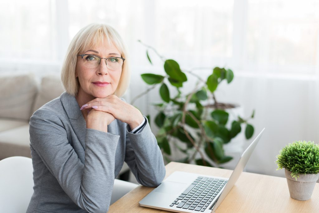 Midlife woman working on a laptop writing her origin story.