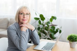 Midlife woman working on a laptop writing her origin story.