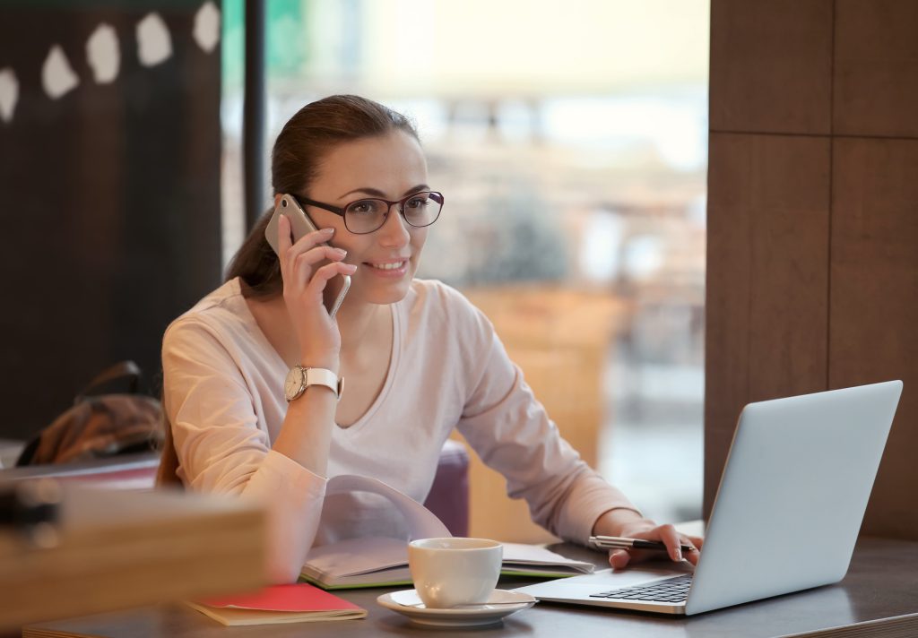 Female coach on a call with a client and taking notes on a computer
